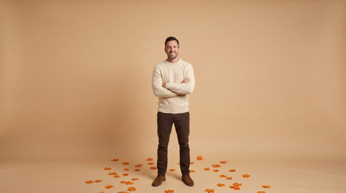 Hombre con jersey de ochos color crudo en un estudio con hojas de otoño